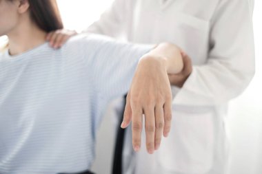 Kadın fizyoterapistler, omuz yaralanması olan hastalara rehabilitasyon merkezinde kas tedavisi için omuzlarına masaj yapıyorlar. Fizyoterapi kavramları.