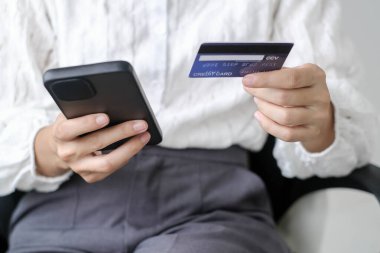 Asyalı kız internet üzerinden alışveriş yapıyor ve akıllı telefon kullanıyor. Cep telefonu numaralarını internet mağazasından satın almak ve ödemek için cep telefonu uygulamasına girin..