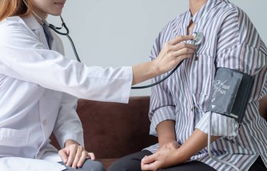 Kadın doktor kan basıncını ölçtü, hasta kalp atışlarını inceledi ve sağlık hizmetleri hakkında konuşmak için oturdu. sağlık hizmeti kavramı.