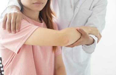 Kadın fizyoterapistler, dirsek yaralanması olan kadın hastalara rehabilitasyon merkezlerindeki hastaları muayene etmeleri için fiziksel yardım sağlıyorlar. Fizyoterapi kavramları.