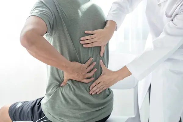 Erkek hastalar muayene ve tedavi için düşük bel ağrısı olan fizyoterapistlere danıştılar. Rehabilitasyon fizyoterapi konsepti.