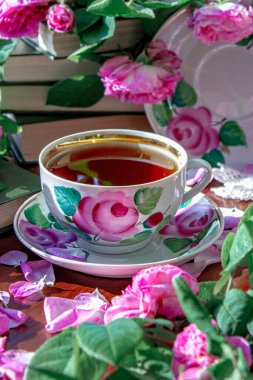 Pembe kokulu güllerle çevrili bir fincan çay..