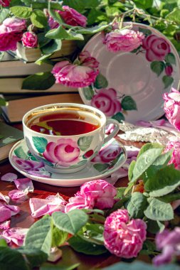 Pembe kokulu güllerle çevrili bir fincan çay..