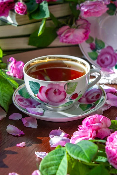 stock image A cup of tea surrounded by pink fragrant roses.