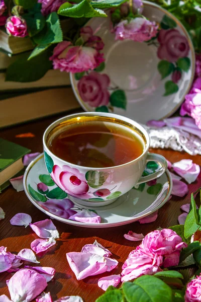 stock image A cup of tea surrounded by pink fragrant roses.