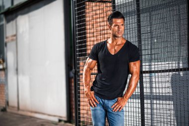 Yakışıklı atletik genç adam sokakta dikiliyor.