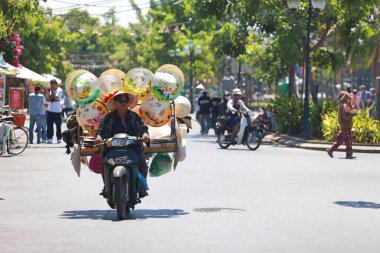 Hoi An, Vietnam 7 Temmuz 2024: Hawker vietness konik şapkalarını bisiklet üzerinde sattı. Eski kasaba, 15. yüzyıldan 19. yüzyıla kadar uzanan bir Güneydoğu Asya ticaret limanı..
