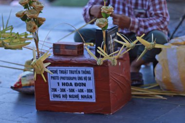 Hoi An, Vietnam 7 Temmuz 2024: İşportacı çekirgeyi satar, çimen dokuması ile yapılır. Çim dokuma geleneksel bir sanat dokuma becerisidir..