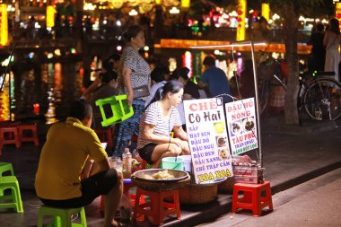 Hoi An, Vietnam 7 Temmuz 2024: Hawker, Hoi An gece pazarında hindistan cevizli ipek kek satıyor. Eski şehir, 15. yüzyıldan 19. yüzyıla kadar uzanan bir Güneydoğu Asya ticaret limanıdır..