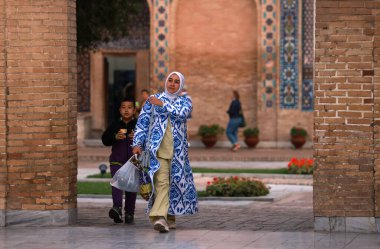Semerkand, Özbekistan 2 Ekim 2024: çocuklu bir anne sokakta yürüyor. Özbek aile yapısında önemli bir rol oynayan kadınlar, sağlarıyla ilgili farklı sorunlarla karşı karşıya.