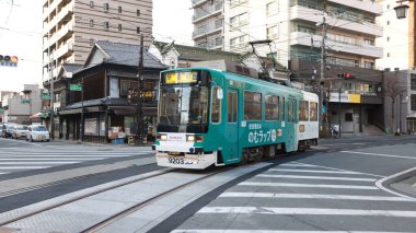 Kumamoto, Japonya - 15 Ocak 2025: Nagasaki Jiro Kissa Shitsu adlı eski kahve dükkanından tramvay geçişi. Kumamoto 'nun tarihi ve geleneksel kafelerinden biridir..