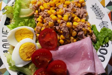 Bir tabak taze sebze ve masada jambon.