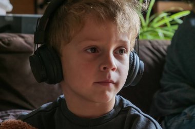Kulaklıkla televizyon izleyen genç bir çocuk.