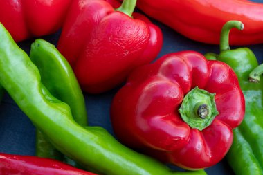 Siyah bir masada kırmızı ve yeşil organik biber.