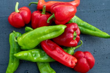 Siyah bir masada kırmızı ve yeşil organik biber.