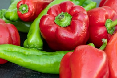 Siyah bir masada kırmızı ve yeşil organik biber.