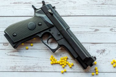 Beyaz ahşap arka planda sarı panjurlu yumuşak bir tabanca.