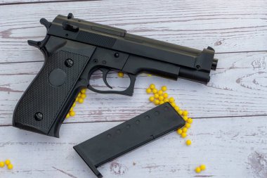 Beyaz ahşap arka planda sarı panjurlu yumuşak bir tabanca.