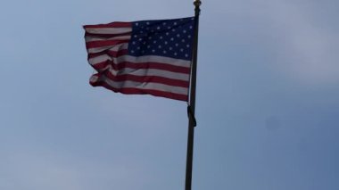 Rüzgarda dalgalanan Amerikan Bayrağı mavi bir arka planda