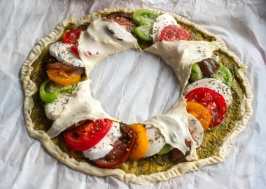 Domates, biber ve peynir gibi çeşitli sebzelerle dolu bir pizza. Pizzalar çelenk şeklinde.