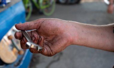 Bir adamın eli üzerinde toprak olan bir İngiliz anahtarını tutuyor. Sıkı çalışma ve ağır işçilik kavramı