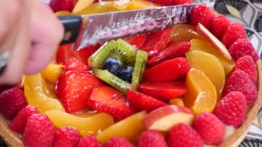 Bıçak, çilek, kivi ve ahududu ile meyveli turta keser.