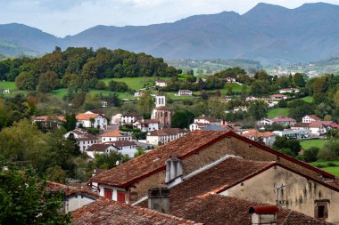 Saint Jean Pied de Port, evler ve bir kilise. Evlerin çoğu beyaz ve kilise kahverengi. Kasaba dağlarla çevrili.