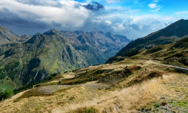 Dağlar yemyeşil ağaçlarla çevrili, gök de bulutlarla çevrili. Manzara huzurlu ve huzurlu. Pireneler, Fransa