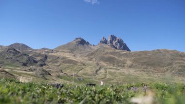 Pic du Midi d Ossau, arka planda açık mavi gökyüzü olan Fransız Pyrenes. Dağlar çimlerle kaplı.