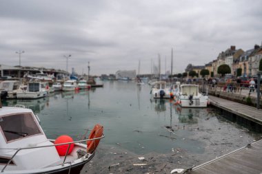 Üzerinde turuncu bir can yeleği olan bir tekne kirli bir su kütlesinin içinde yüzüyor. Su bulanık ve plastik şişeler ve diğer çöpler de dahil olmak üzere enkazlarla dolu.