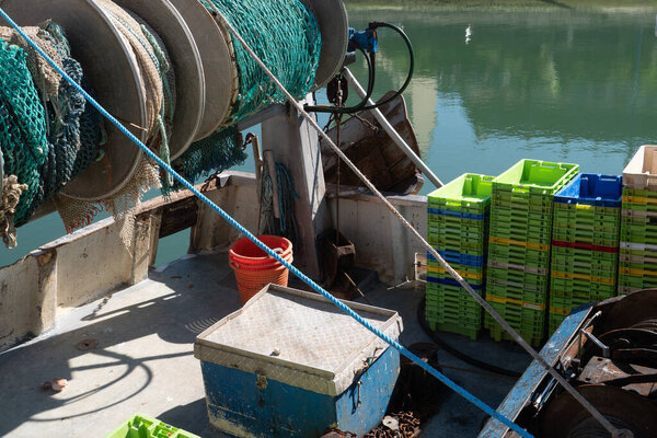 A boat with a blue box on it and a green crate. The crate is full of green boxes