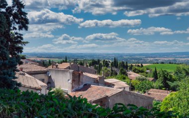 Fransa 'nın güneyindeki küçük bir kasabanın çatılarının manzarası. Evler taştan yapılmış ve pembe çatıları var..