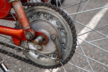 Paslı bisiklet zinciri gümüş bir jant kapağıyla gösterilir. Zincirin birkaç halkası eksik.