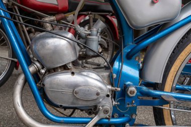 Motosiklet motoru bir zincir ve zincir koruması eksik bir şekilde yerde oturuyor. Zincir koruyucu genelde zinciri toprak ve molozlardan korumak için kullanılır ama bu olayda kayıp.