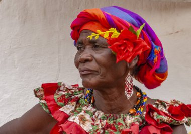 PALENQUERA, CARTAGENA, COLOMBIA, 20 Şubat 2024: Eski Cartagena kasabasındaki neşeli taze meyve sokak satıcısı namı diğer Palenquera. Geleneksel giyinmiş mutlu Afro-Kolombiyalı kadın, Kolombiya kültürü.