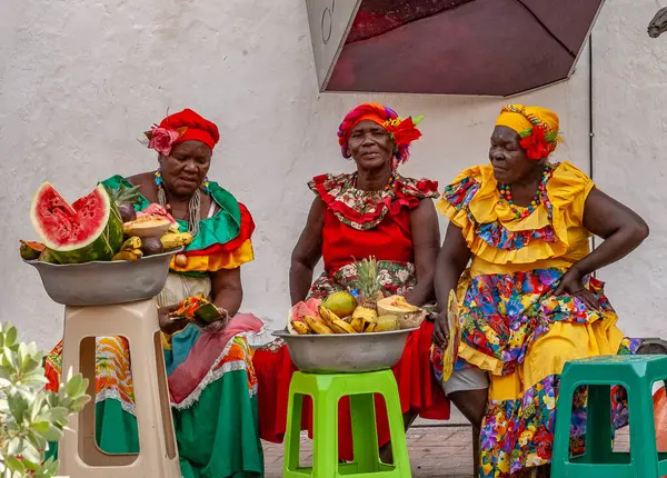 PALENQUERA, CARTAGENA, COLOMBIA, 20 Şubat 2024: Eski Cartagena kasabasındaki neşeli taze meyve sokak satıcısı namı diğer Palenquera. Geleneksel giyinmiş mutlu Afro-Kolombiyalı kadın, Kolombiya kültürü.