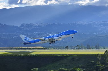 Dağların, bulutların ve güneşin ortasında bir kargo uçağı kalkıyor..