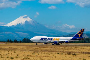 Yoğun öğle güneşinin altında, bir Atlas Air Boeing 747 Quito Havaalanı pistinde taksiyle giderken bir ısı serabı yaratır. İkonik kar kaplı Cotopaxi volkanı, yerdeki kavurucu manzarayla çelişiyor..