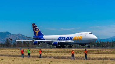 Bir grup gözcü Quito Havaalanı 'ndaki pistte heybetli bir Atlas Hava Kargo uçağının fotoğrafını çekiyor. Bu görüntü havacılık, hava taşımacılığı ve küresel lojistik tutkusunu yakalar..