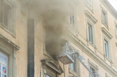 Napoli, İtalya - 15 Şubat 2023 - Pencereden duman yükselen ev yangını. Garibaldi Meydanı, Napoli, İtalya. İtfaiye sepetinde veya kafesinde iki itfaiyeci, manzara.