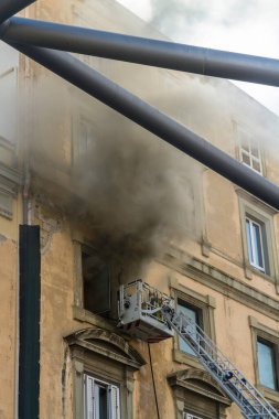 Napoli, İtalya - 15 Şubat 2023 - Pencereden duman yükselen ev yangını. Garibaldi Meydanı, Napoli, İtalya. İtfaiye sepetini veya kafesi tek bir itfaiyeciyle..