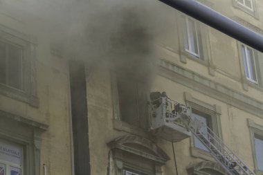 Napoli, İtalya - 15 Şubat 2023 - Pencereden duman yükselen ev yangını. Garibaldi Meydanı, Napoli, İtalya. İtfaiye sepetinden ya da kafesinden iki itfaiyeci, Garibaldi İstasyonu 'ndan, telefoto, sis dumanı..
