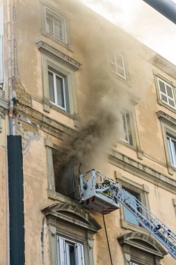Napoli, İtalya - 15 Şubat 2023 - Pencereden duman yükselen ev yangını. Garibaldi Meydanı, Napoli, İtalya. Magirus İtfaiye sepetinde veya kafesinde tek bir itfaiyeci, portre.
