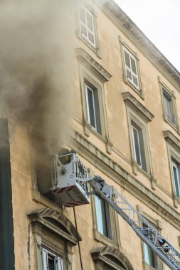 Napoli, İtalya - 15 Şubat 2023 - Pencereden duman yükselen ev yangını. Garibaldi Meydanı, Napoli, İtalya. İtfaiye arabası ya da kafes, iki itfaiyeci, portre..