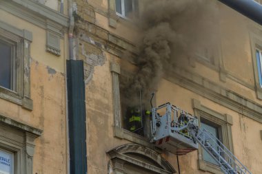 Napoli, İtalya - 15 Şubat 2023 - Pencereden duman yükselen ev yangını. Garibaldi Meydanı, Napoli, İtalya. İtfaiye arabası ya da kafese iki itfaiyeci, biri giriyor..