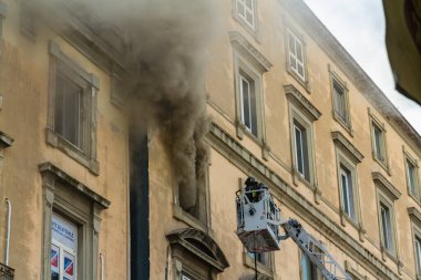 Napoli, İtalya - 15 Şubat 2023 - Pencereden duman yükselen ev yangını. Garibaldi Meydanı, Napoli, İtalya. İtfaiye sepetinde ya da kafesinde iki itfaiyeci solda, manzara.