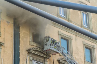 Napoli, İtalya - 15 Şubat 2023 - Pencereden duman yükselen ev yangını. Garibaldi Meydanı, Napoli, İtalya. Garibaldi İstasyonu 'nun tepe örtüsünden iki itfaiyeciyle birlikte itfaiye sepetine ya da kafese.