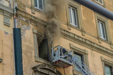 Napoli, İtalya - 15 Şubat 2023 - Pencereden duman yükselen ev yangını. Garibaldi Meydanı, Napoli, İtalya. Magirus İtfaiye sepetinde veya kafesinde tek bir itfaiyeci, manzara.