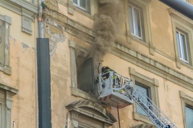 Napoli, İtalya - 15 Şubat 2023 - Pencereden duman yükselen ev yangını. Garibaldi Meydanı, Napoli, İtalya. İtfaiye sepetine veya kafese iki itfaiyeci girdi..