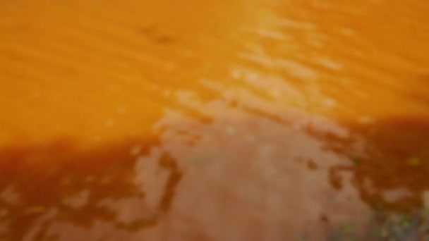 ビデオ オレンジ色の黄色い水の上のリップルのぼやけ散らされたビュー — ストック動画